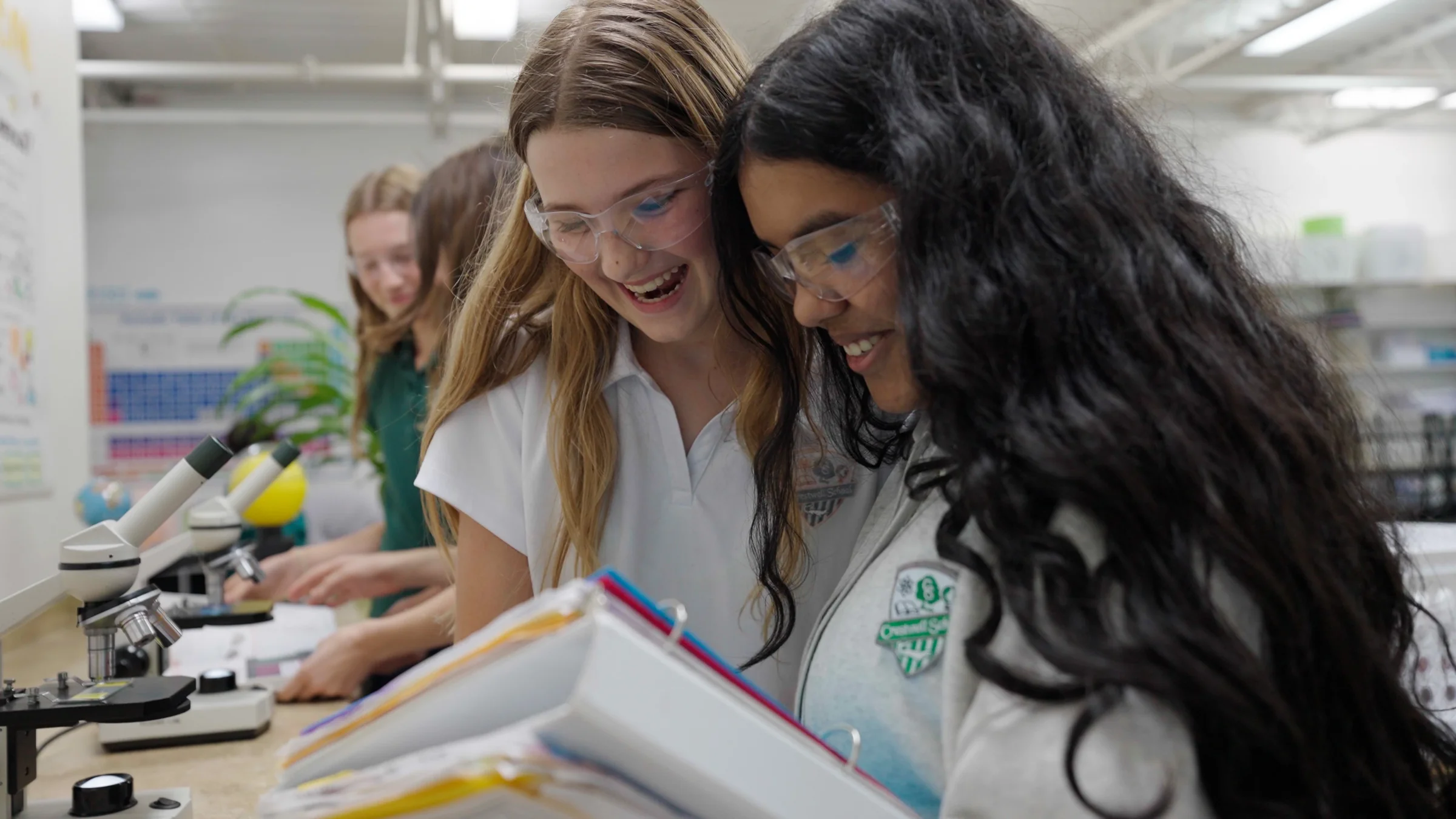 Two students laughing over a microscope